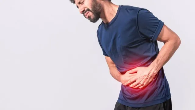 Man holding his abdomen in discomfort, a common colorectal symptom